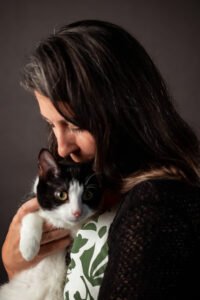 Woman kisses a black and white cat on the head